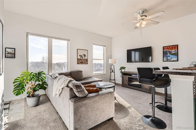 carpeted living area featuring baseboards and ceiling fan