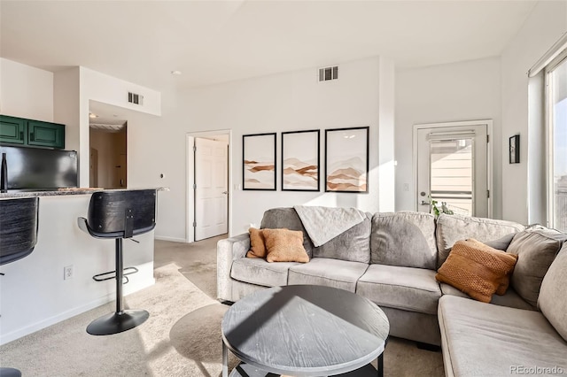 living room featuring baseboards, visible vents, and light carpet