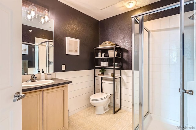 bathroom featuring a shower stall, vanity, tile patterned floors, toilet, and a textured wall