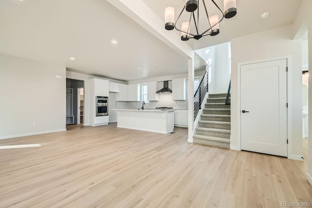 unfurnished living room featuring light hardwood / wood-style flooring, a notable chandelier, and sink