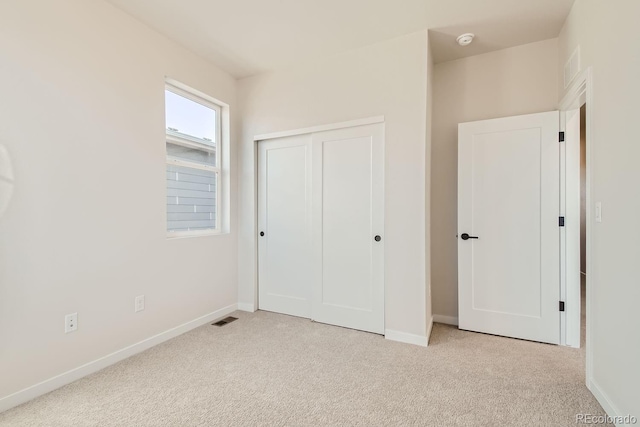 unfurnished bedroom with light colored carpet and a closet