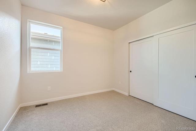 unfurnished bedroom with light carpet and a closet