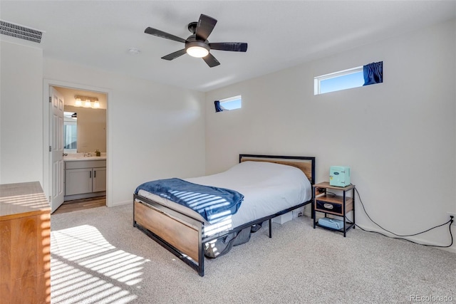 bedroom featuring ensuite bathroom, ceiling fan, light colored carpet, and sink