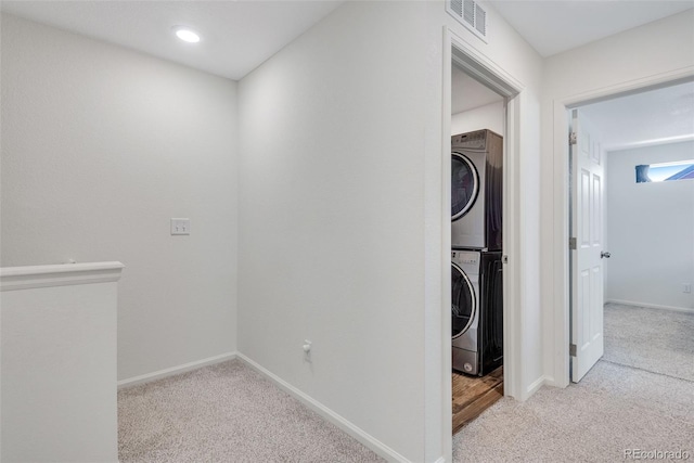 laundry area featuring light colored carpet and stacked washer / dryer