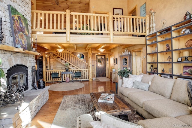 living room featuring hardwood / wood-style floors, a fireplace, wood walls, and a towering ceiling