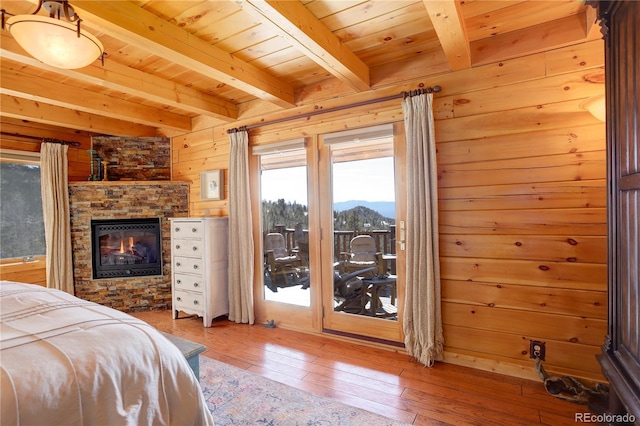 bedroom featuring a fireplace, wooden ceiling, wood-type flooring, and wooden walls