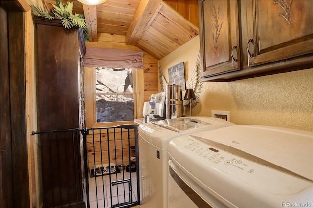 laundry area with cabinets, washer and clothes dryer, wood ceiling, and wooden walls