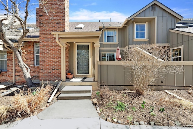 7707 S Curtice Way Unit D, Littleton, CO 80120 - view of front of home with board and batten siding, a chimney, a shingled roof, and brick siding