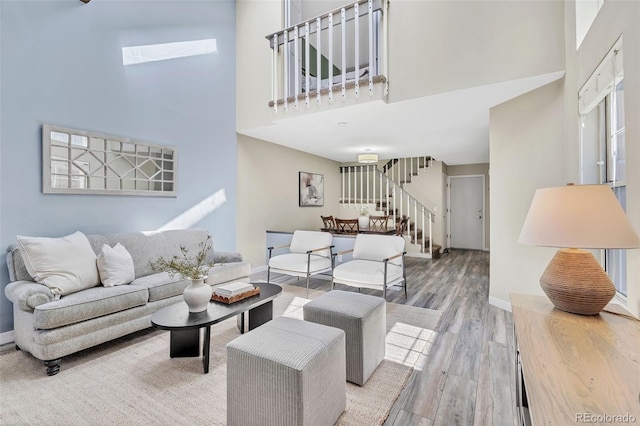 7707 S Curtice Way Unit D, Littleton, CO 80120 - living area featuring stairway, a towering ceiling, wood finished floors, and baseboards