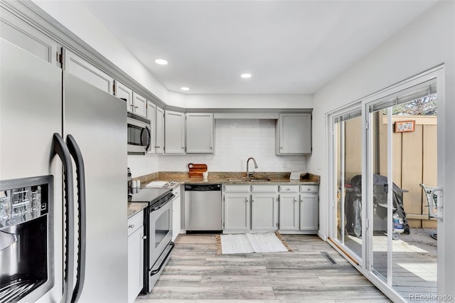 7707 S Curtice Way Unit D, Littleton, CO 80120 - kitchen featuring stainless steel appliances, a sink, light wood-style floors, dark stone countertops, and recessed lighting