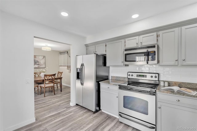 7707 S Curtice Way Unit D, Littleton, CO 80120 - kitchen with appliances with stainless steel finishes, decorative backsplash, light wood-type flooring, baseboards, and light stone countertops