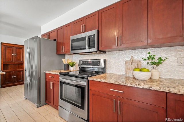 kitchen featuring tasteful backsplash, light stone countertops, and appliances with stainless steel finishes