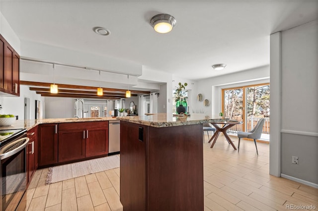 kitchen with decorative light fixtures, light wood-type flooring, appliances with stainless steel finishes, and sink