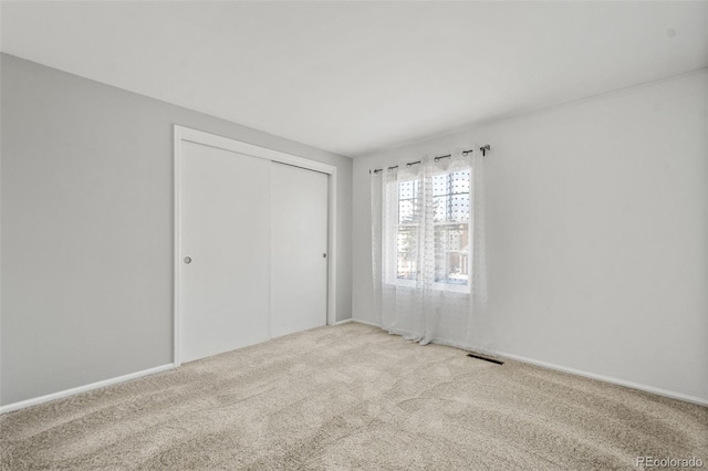 unfurnished bedroom featuring light carpet and a closet