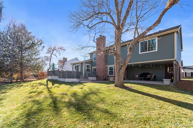 back of property featuring a lawn, a deck, and a patio