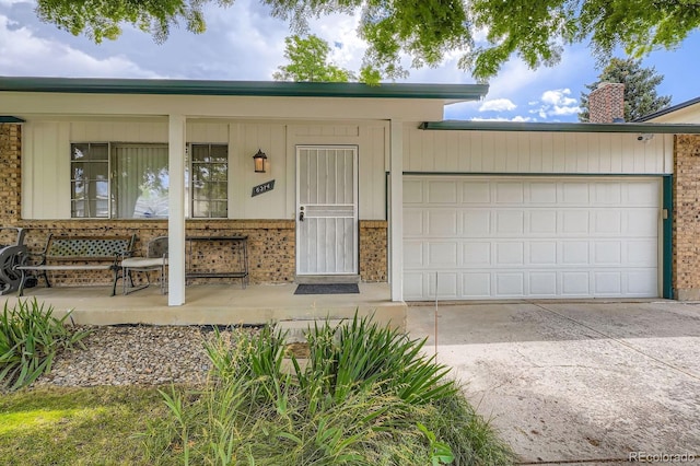 6314 S Johnson St, Littleton, CO 80123 - view of front of home featuring driveway, covered porch, brick siding, a chimney, and a garage