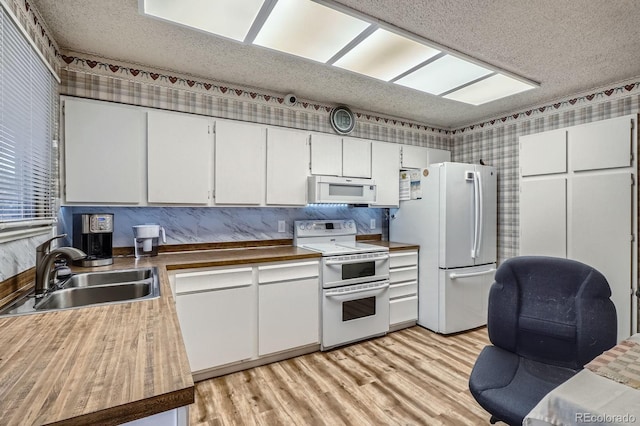 6314 S Johnson St, Littleton, CO 80123 - kitchen with white appliances, a textured ceiling, wallpapered walls, white cabinets, and light wood-style floors