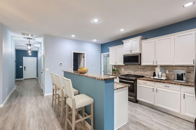 449 Vista Blvd, Lochbuie, CO 80603 - kitchen with stainless steel appliances, a breakfast bar, backsplash, light wood-style flooring, and stone countertops