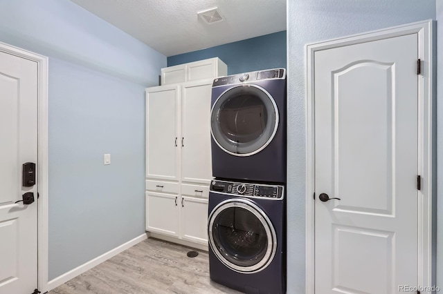 449 Vista Blvd, Lochbuie, CO 80603 - laundry room with stacked washer / dryer, cabinet space, and light wood-type flooring