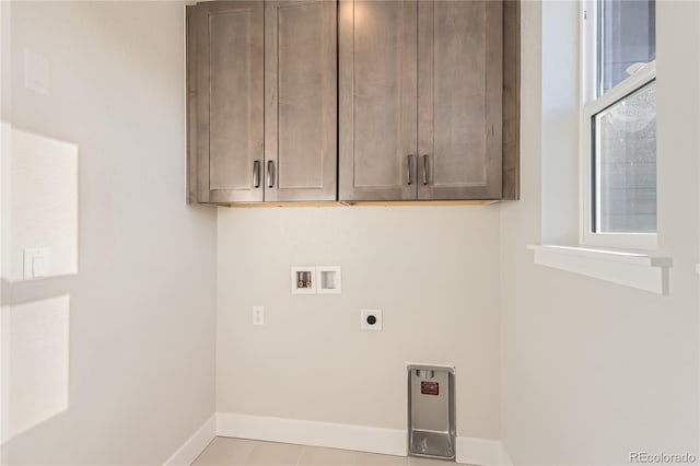 clothes washing area featuring cabinets, hookup for a washing machine, light tile patterned floors, and electric dryer hookup