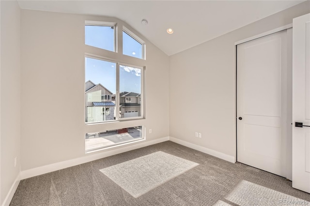 carpeted empty room with vaulted ceiling