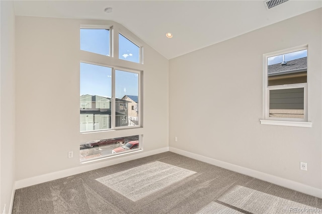 spare room featuring carpet flooring, a healthy amount of sunlight, and vaulted ceiling