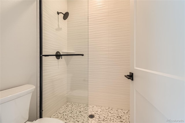 bathroom with a tile shower and toilet