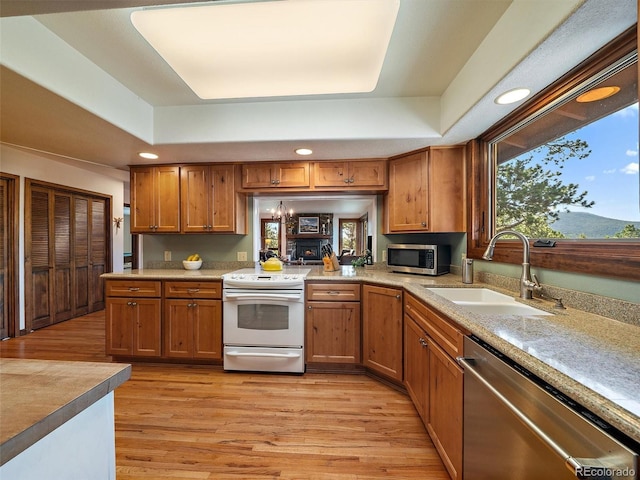 28550 Cavan Ln, Evergreen, CO 80439 - kitchen featuring stainless steel appliances, a raised ceiling, light wood finished floors, brown cabinets, and recessed lighting