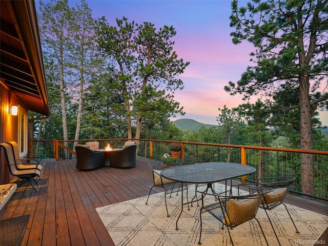 28550 Cavan Ln, Evergreen, CO 80439 - deck at dusk featuring an outdoor fire pit, outdoor dining space, and a mountain view