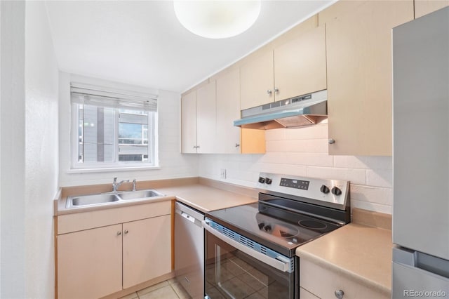 kitchen featuring stainless steel appliances, under cabinet range hood, a sink, light countertops, and backsplash