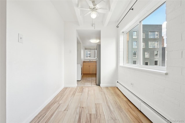 corridor featuring baseboard heating, light wood finished floors, beamed ceiling, baseboards, and a sink