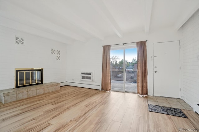 250 N Pearl St Unit 310, Denver, CO 80203 - unfurnished living room with a baseboard heating unit, beam ceiling, wood finished floors, an AC wall unit, and a tiled fireplace