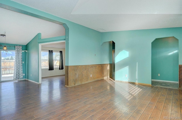 spare room featuring lofted ceiling, dark hardwood / wood-style floors, and a textured ceiling