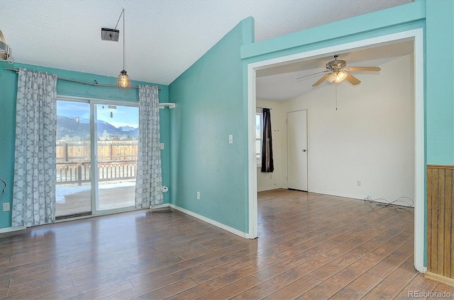 unfurnished room with a mountain view, a textured ceiling, lofted ceiling, and dark hardwood / wood-style flooring