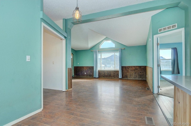 interior space with lofted ceiling, dark hardwood / wood-style floors, and a textured ceiling