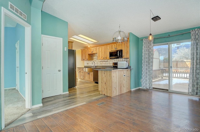 kitchen featuring hardwood / wood-style floors, backsplash, hanging light fixtures, stainless steel appliances, and light brown cabinets