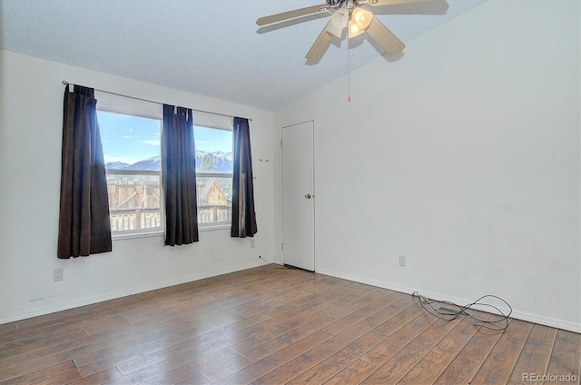 empty room featuring lofted ceiling, dark wood-type flooring, a textured ceiling, and ceiling fan