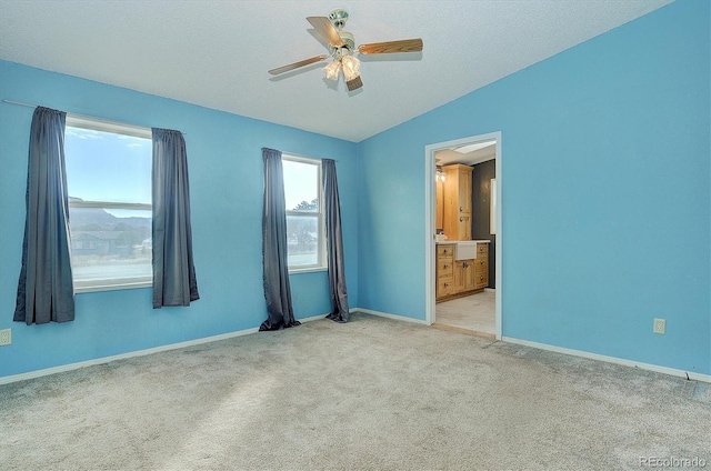 carpeted spare room with a textured ceiling, vaulted ceiling, and ceiling fan