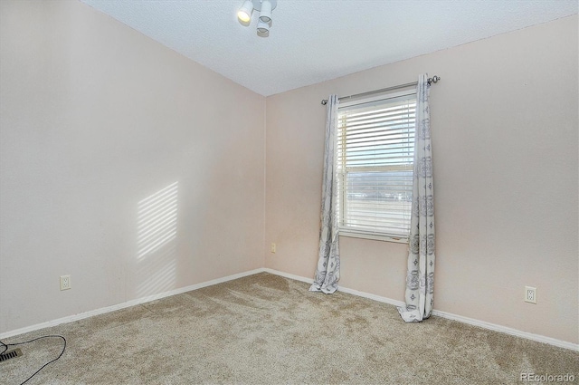 spare room with light colored carpet and a textured ceiling