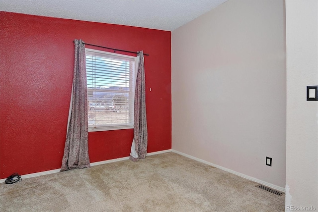 empty room with light colored carpet and a textured ceiling