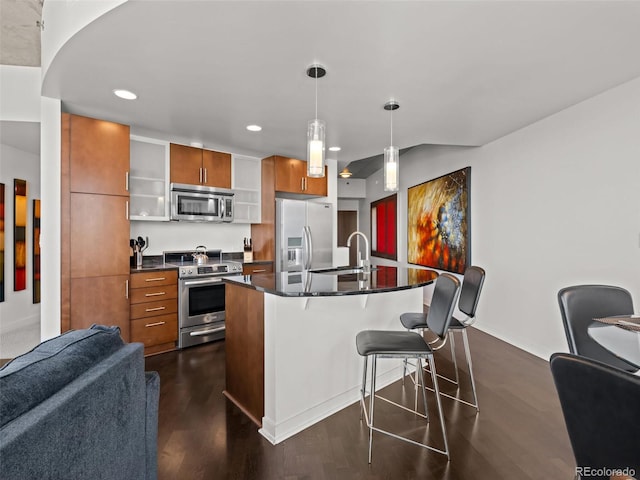 891 14th St Unit 3411, Denver, CO 80202 - kitchen featuring appliances with stainless steel finishes, brown cabinets, dark countertops, a kitchen breakfast bar, and recessed lighting