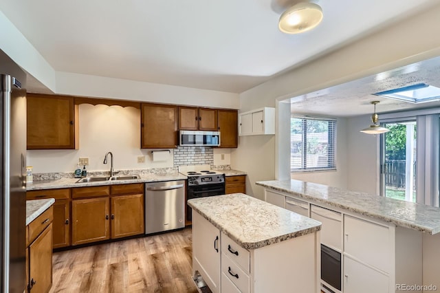 912 S Kingston St, Aurora, CO 80012 - kitchen featuring appliances with stainless steel finishes, a sink, brown cabinets, and a center island