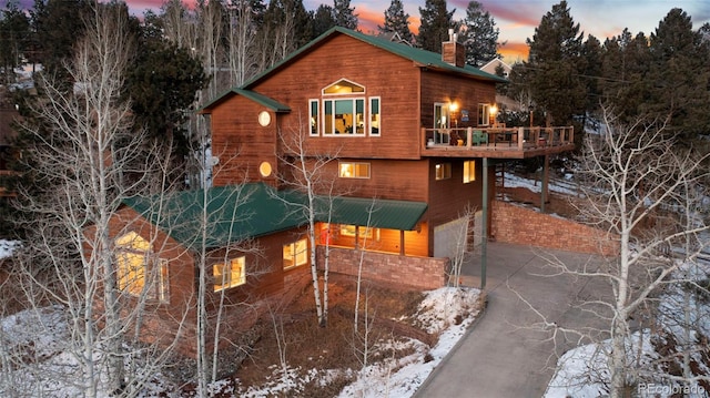 snow covered house featuring a deck and a garage