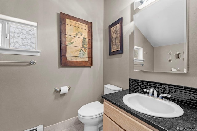 bathroom with toilet, decorative backsplash, lofted ceiling, a baseboard heating unit, and vanity