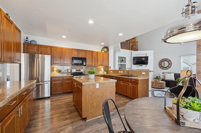kitchen with backsplash, a center island, appliances with stainless steel finishes, a sink, and brown cabinetry