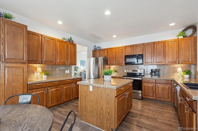 kitchen with dark wood-style flooring, stainless steel appliances, backsplash, and a center island