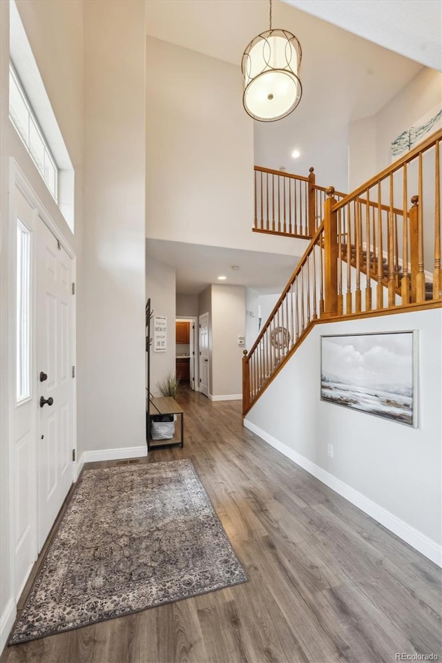 foyer with baseboards, stairway, a towering ceiling, and wood finished floors