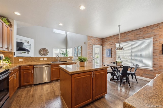 kitchen featuring hanging light fixtures, a sink, stainless steel appliances, light wood-type flooring, and light countertops
