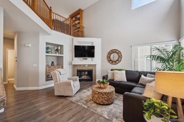 8114 Briar Ridge Dr, Castle Pines, CO 80108 - living room with a towering ceiling, wood finished floors, baseboards, a tiled fireplace, and built in shelves