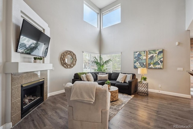 8114 Briar Ridge Dr, Castle Pines, CO 80108 - living room featuring a tiled fireplace, baseboards, healthy amount of natural light, and a towering ceiling